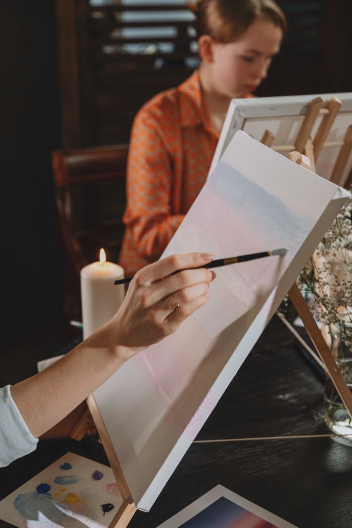 Close-up of a person painting on a canvas during an art class.