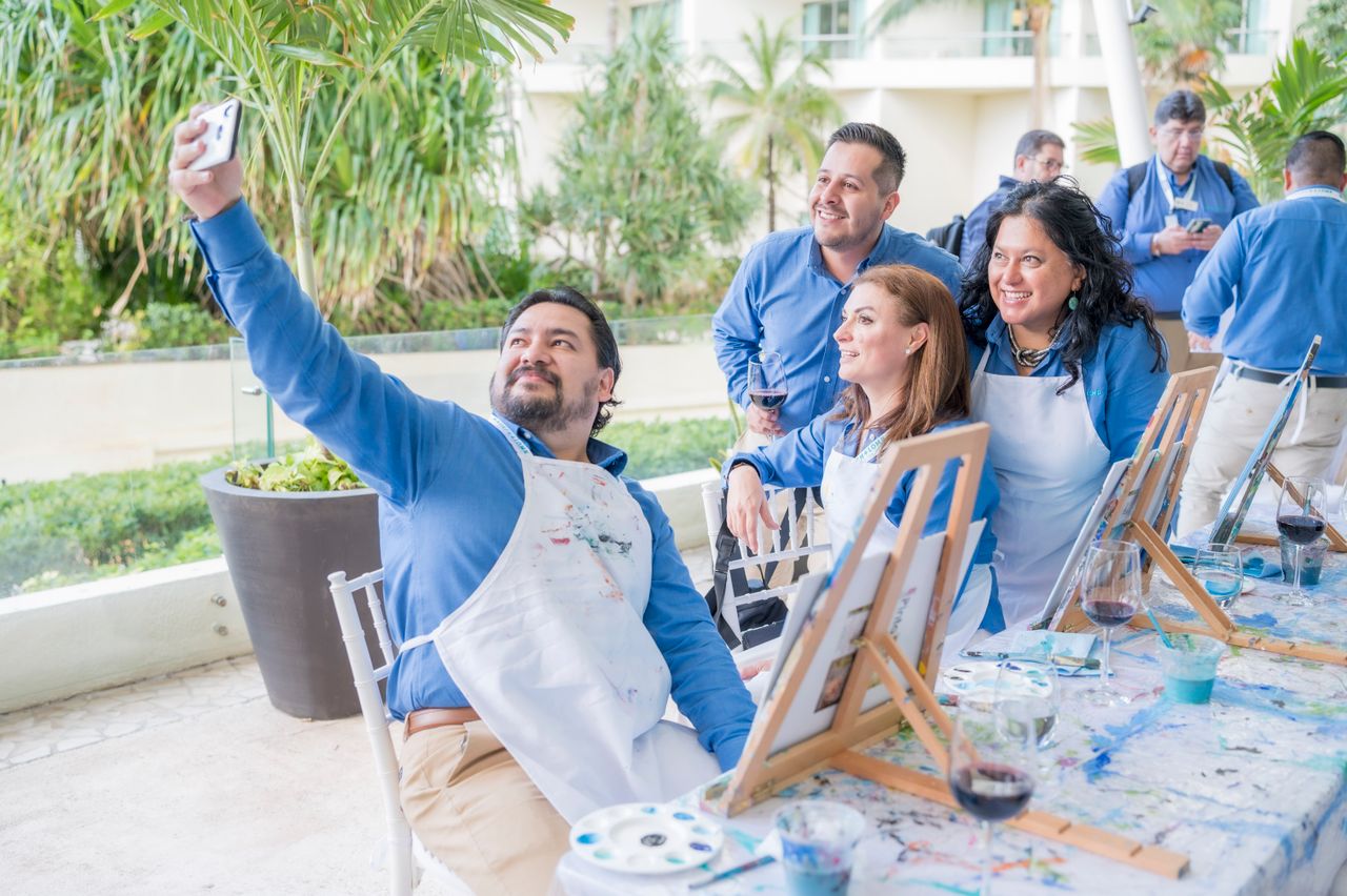 Home Adults enjoy a group painting workshop, capturing a fun selfie together.