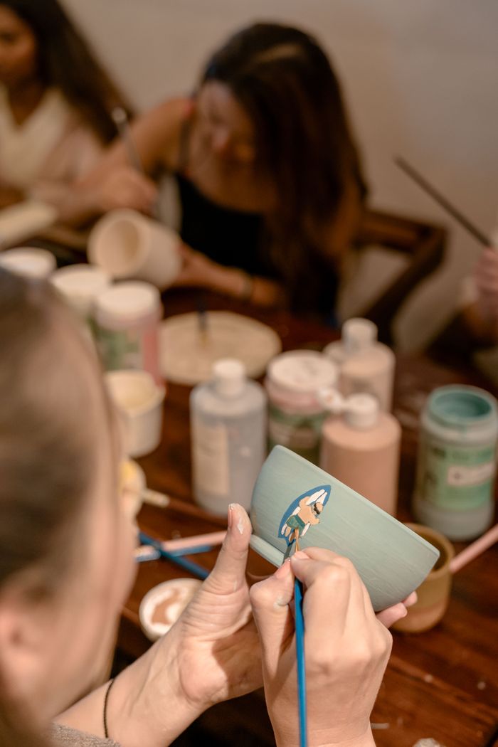Offerings Adults engaging in a pottery workshop in Maldives, focusing on painting and glazing ceramic bowls.