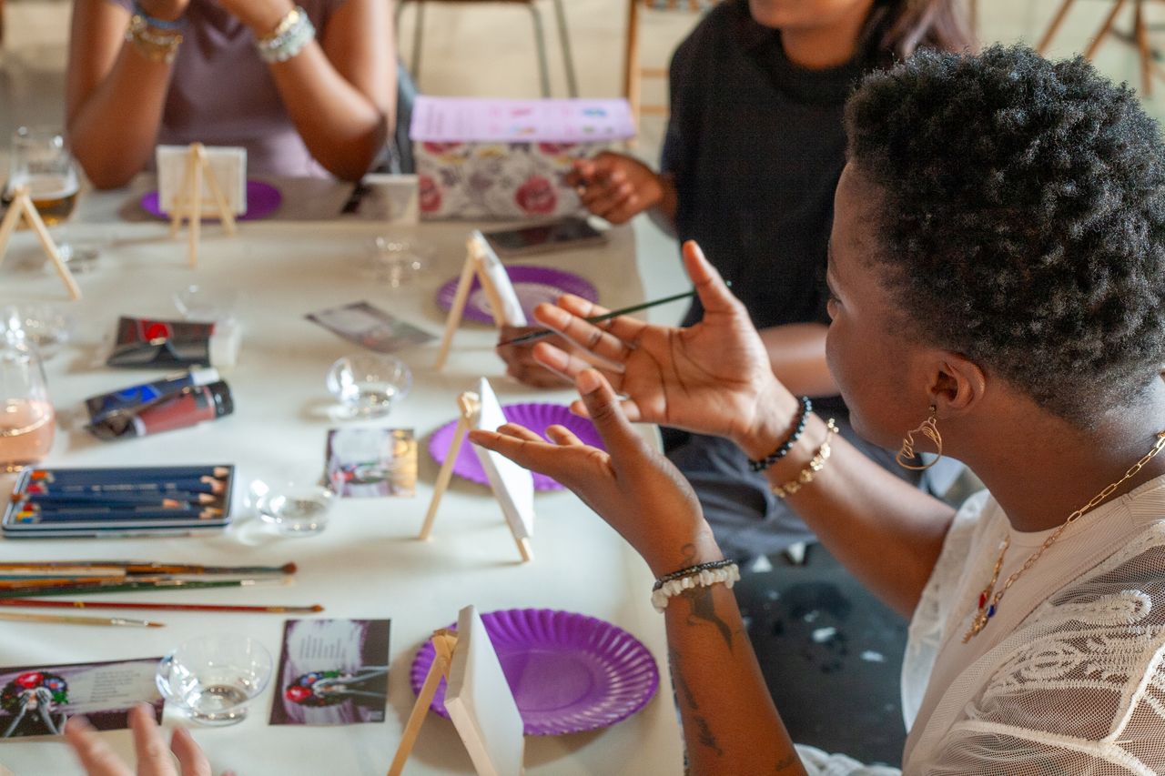 Home A diverse group of adults participating in an indoor painting workshop with canvases and brushes.