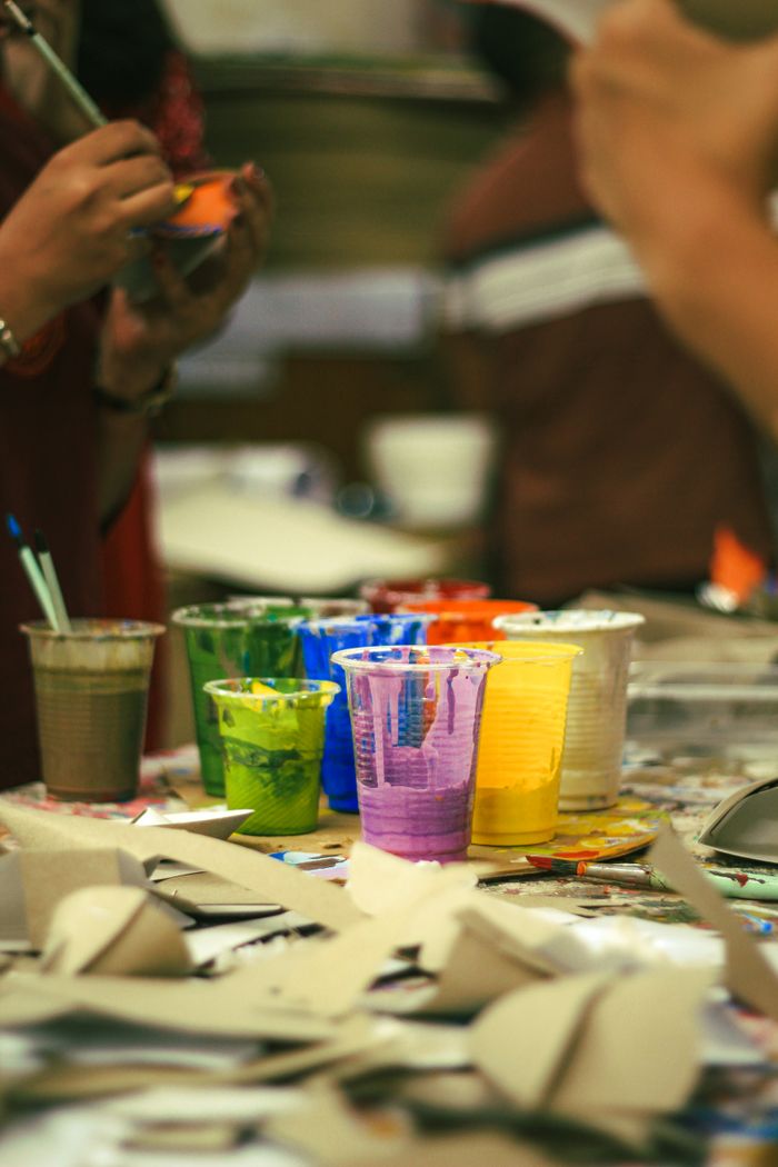 Vibrant art supplies and paints on a table in an art classroom in Dhaka.