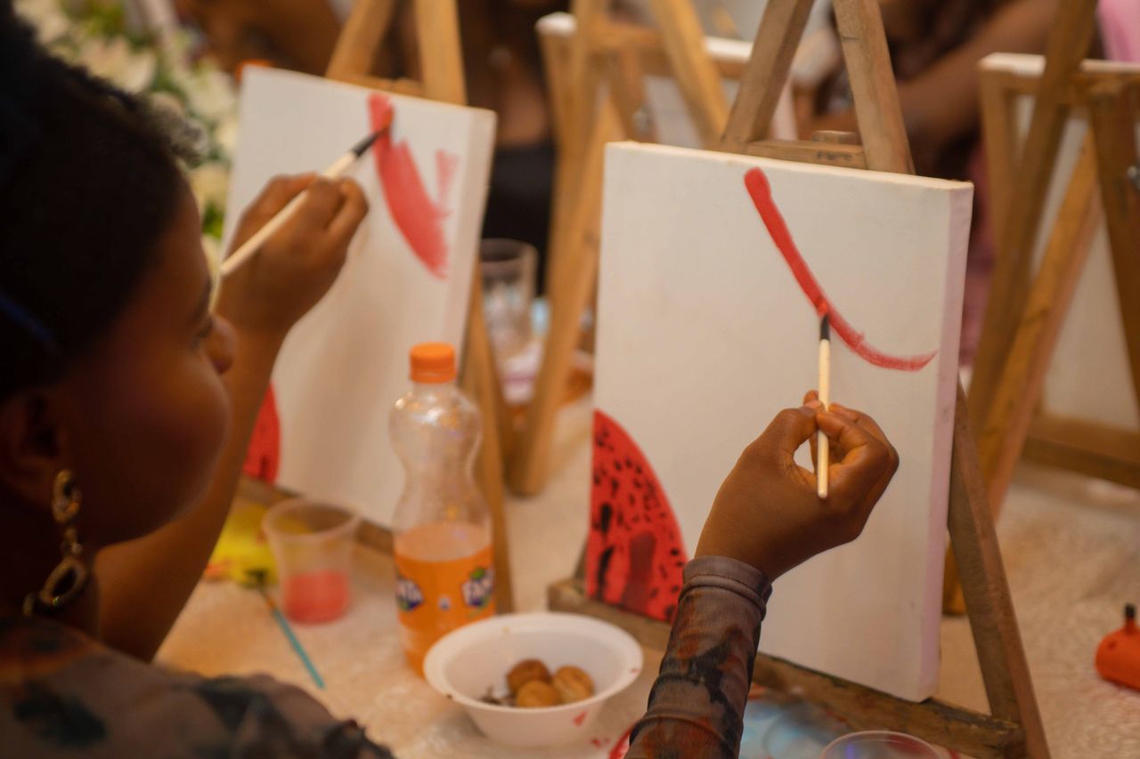 Offerings Participants enjoying a hands-on painting session in a lively indoor workshop setting.