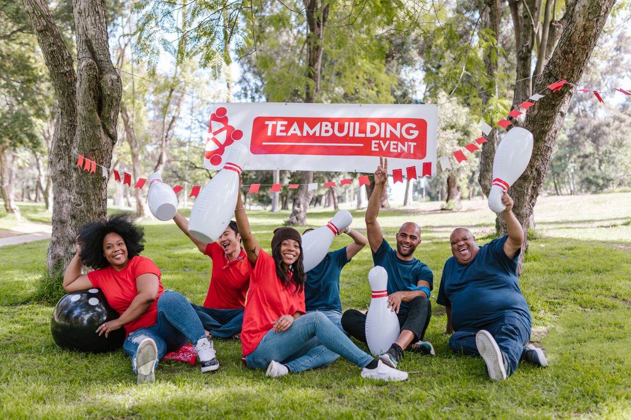 About Cheerful group of diverse adults enjoy a team building event outdoors with bowling props.